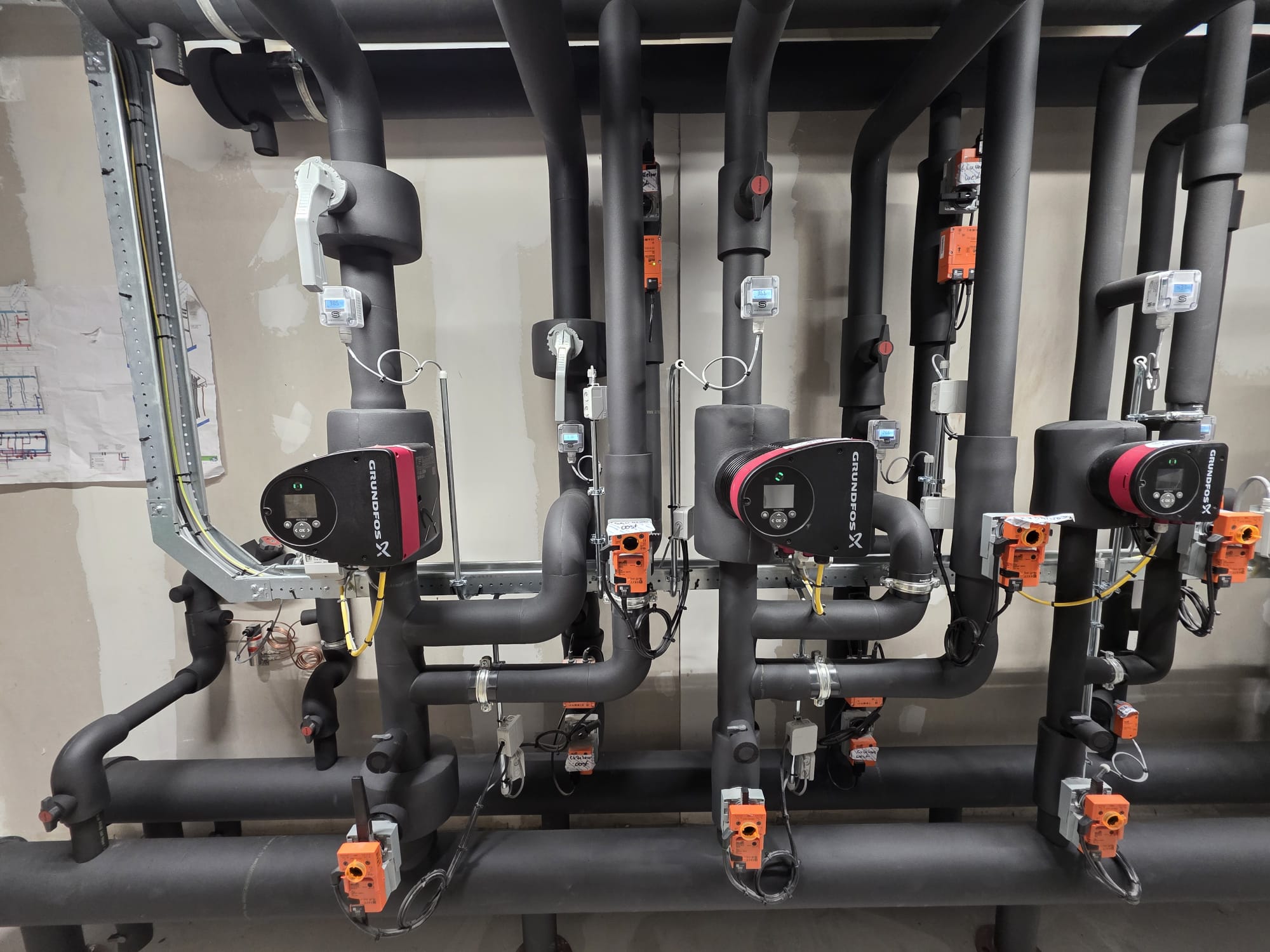 Warmtepomp installatie met geïsoleerde leidingen en afsluiters in technische ruimte