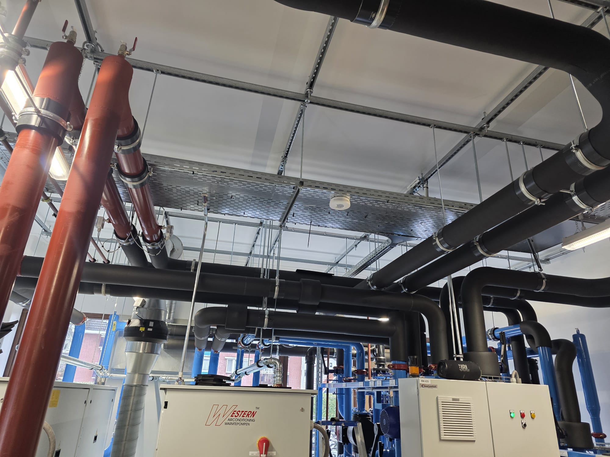 Overzicht van technische ruimte met warmtepompinstallaties en leidingwerk