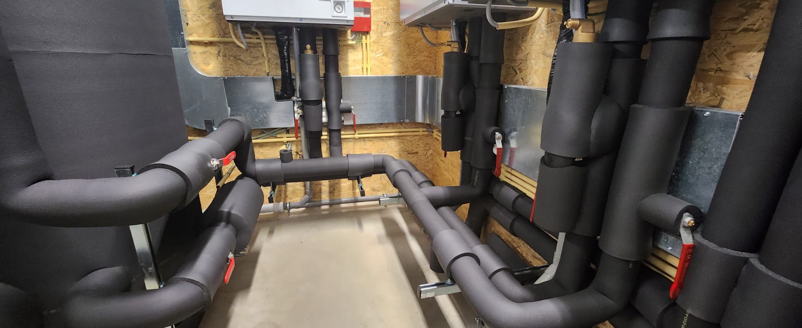 Geïsoleerde warmtepomp leidingen langs plafon en grond in professionele installatie