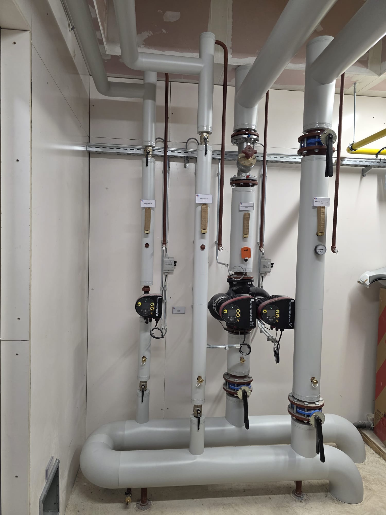 Technische ruimte met warmtepomp en geïsoleerde verwarmingsleidingen